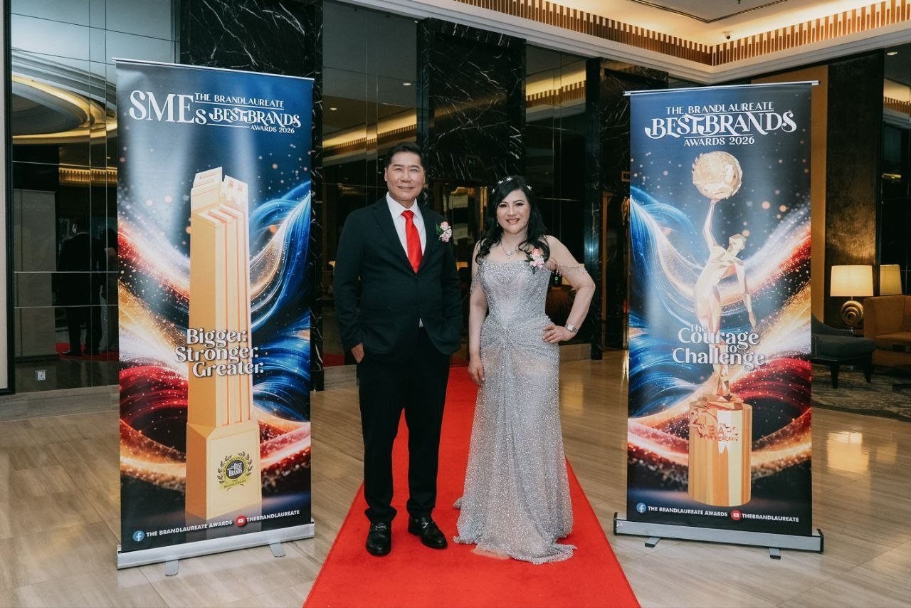 DR. J AARON K DAVID and DR. SHEKINAIH SIEW SIN YAP stand on the red carpet between the banners of The BrandLaureate SMEs BestBrands Awards and The BrandLaureate BestBrands Awards