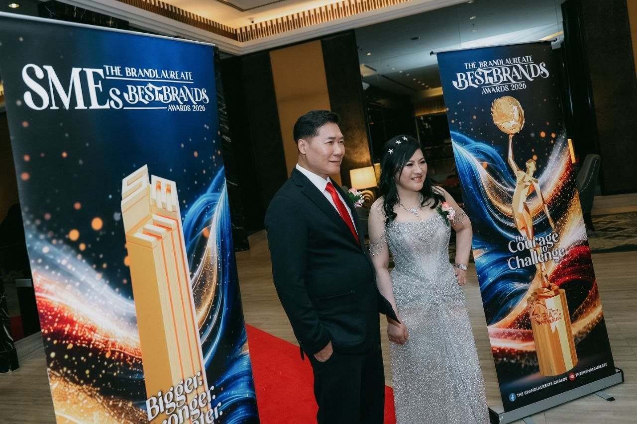 DR. SHEKINAIH SIEW SIN YAP and DR. J AARON K DAVID stand together on the red carpet between banners for The BrandLaureate SMEs BestBrands Awards 2026 and The BrandLaureate BestBrands Awards 2026