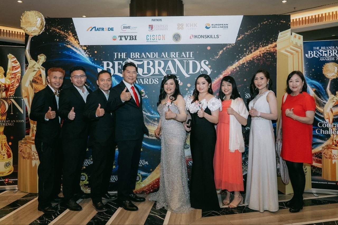 The same line-up before The BrandLaureate BestBrands Awards 2026 backdrop, with DR. J AARON K DAVID, DR. SHEKINAIH SIEW SIN YAP, Hilary Ng, Florence in her ivory gown and the team of CE Global Network International and Crowned Eagles Global all giving a thumbs-up.