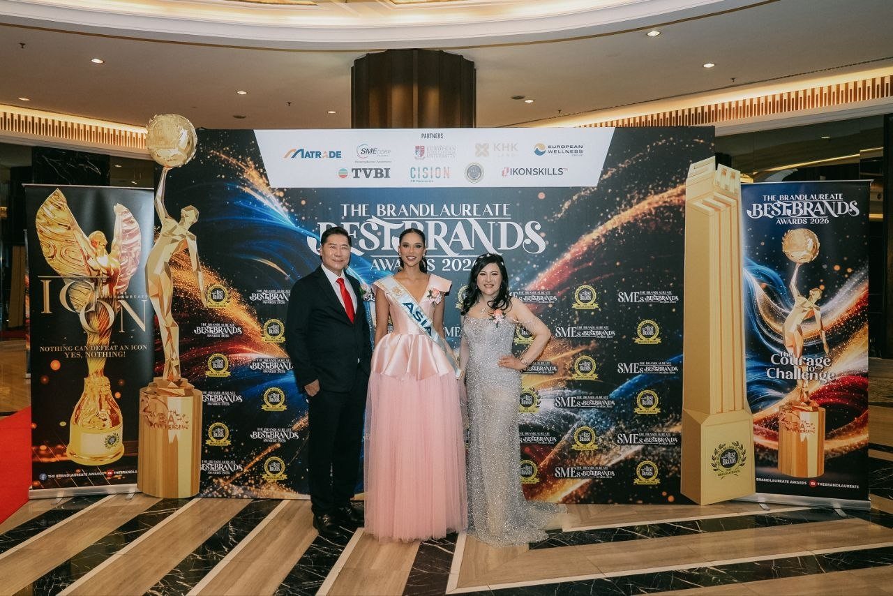 DR. J AARON K DAVID, Miss Universe Malaysia in a pink gown and sash, and DR. SHEKINAIH SIEW SIN YAP stand together at The BrandLaureate BestBrands Awards 2026 backdrop