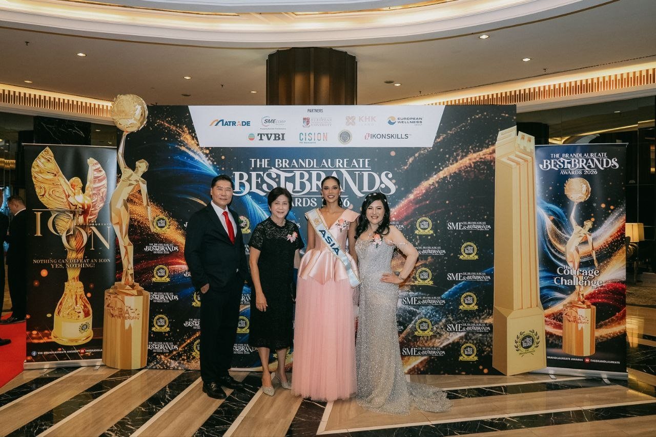 DR. J AARON K DAVID and DR. SHEKINAIH SIEW SIN YAP with Miss Universe Malaysia and a key member of The BrandLaureate team at The BrandLaureate BestBrands Awards 2026 backdrop, beside the tall gold trophy replicas