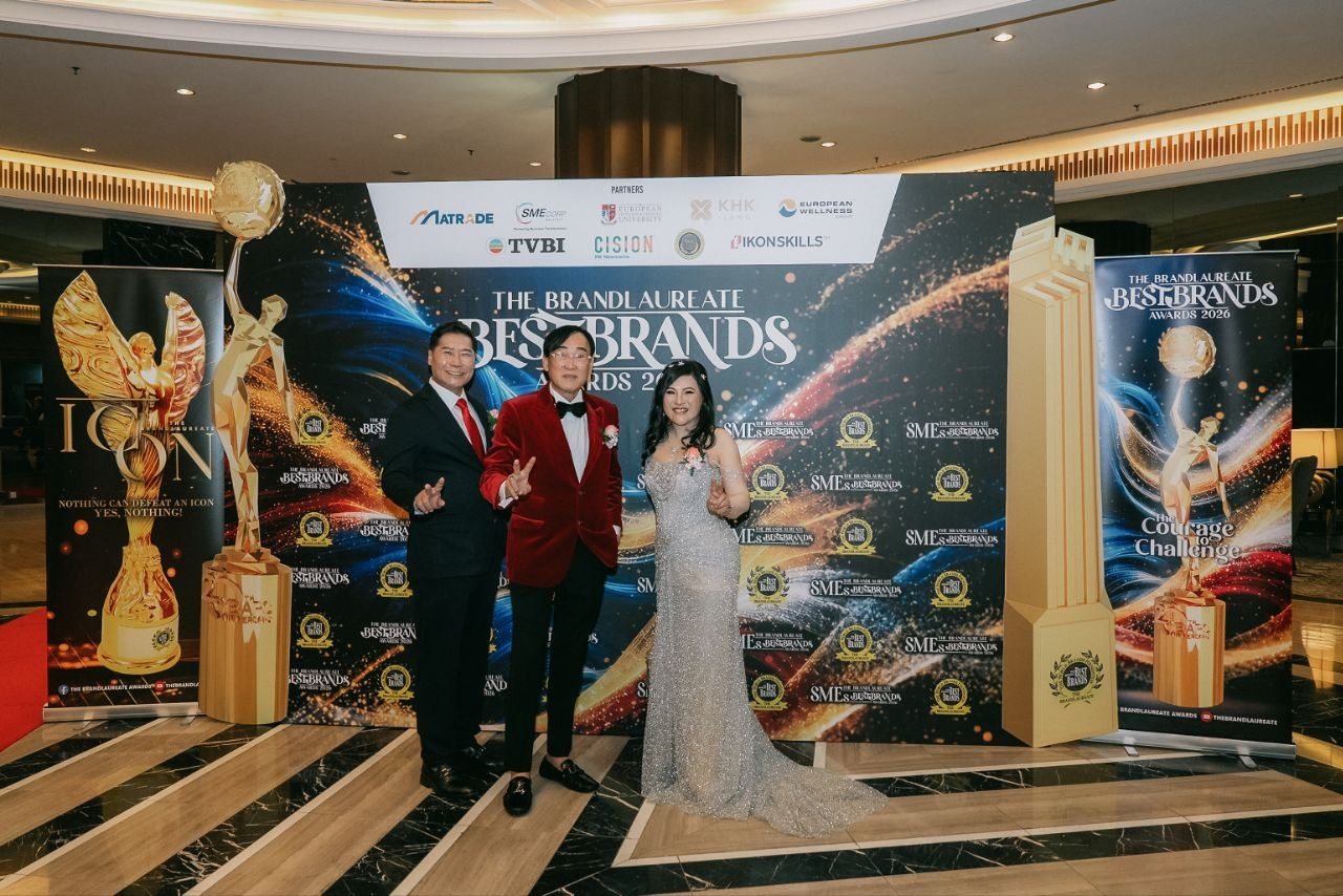 DR. J AARON K DAVID, Prof. Dr. KKJohan in a red velvet dinner jacket, and DR. SHEKINAIH SIEW SIN YAP stand before The BrandLaureate BestBrands Awards 2026 backdrop between the gold trophy replicas