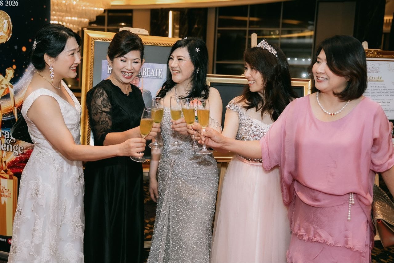 DR. SHEKINAIH SIEW SIN YAP and four women guests in evening gowns raise glasses of champagne together beside framed portraits