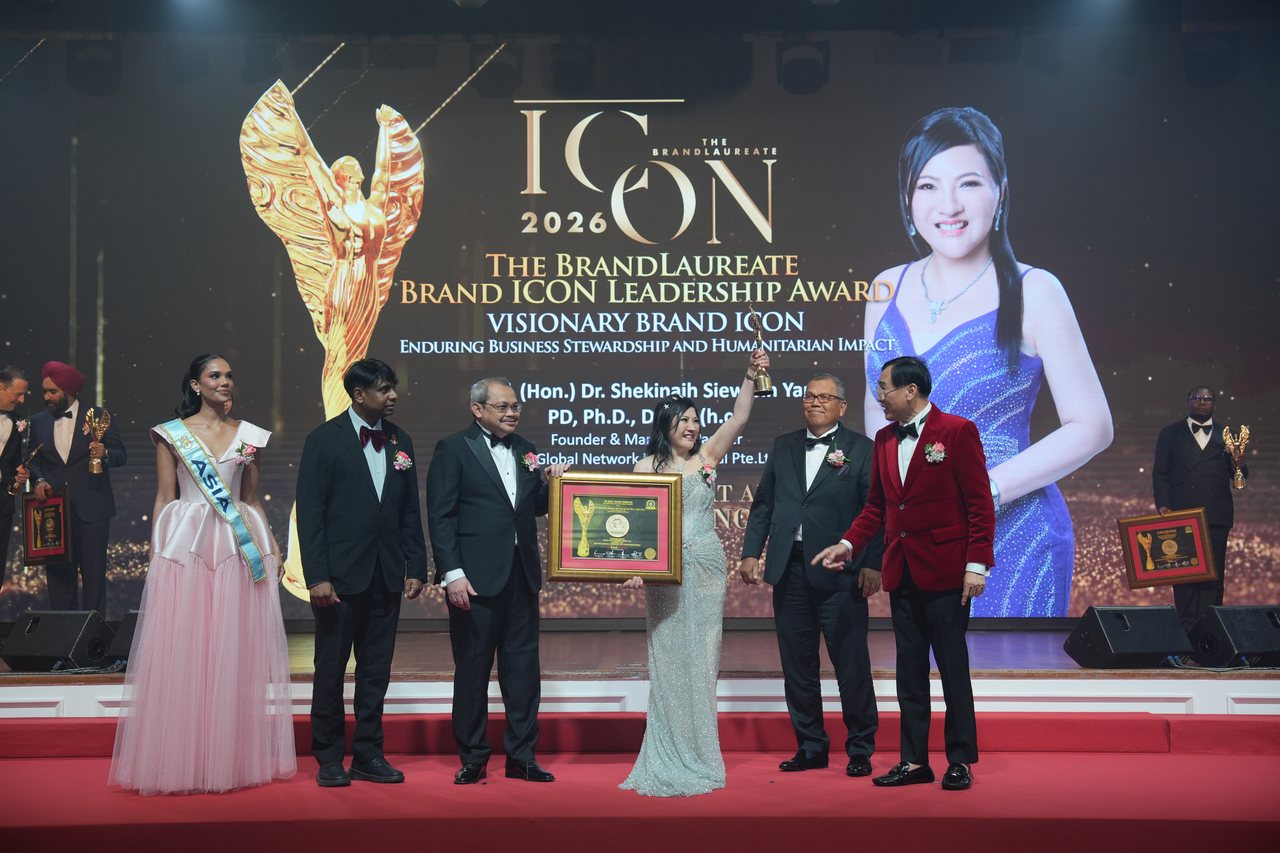The full stage with DR. SHEKINAIH SIEW SIN YAP at the centre holding her certificate and trophy among the presenters, Prof. Dr. Edward Roy Krishnan standing at left, Tun Md Raus Sharif beside her and Prof. Dr. KKJohan in a red velvet jacket, beneath the large screen with her portrait and award title