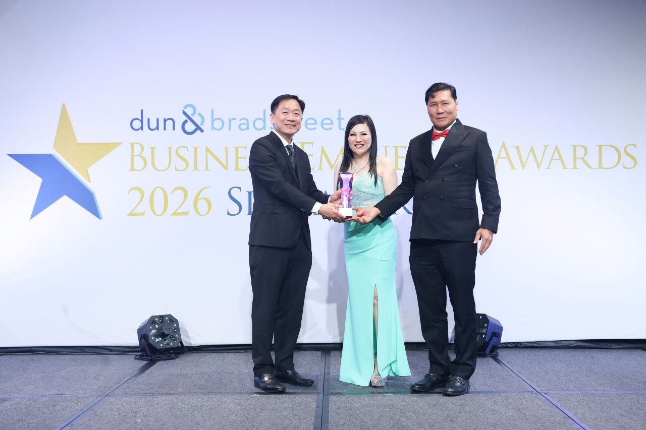 On stage at the Business Eminence Awards 2026, SHEKINAIH SIEW SIN YAP and J AARON K DAVID receive the company's trophy from the presenter, in front of the Dun & Bradstreet backdrop