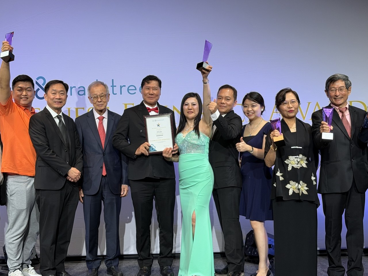 SHEKINAIH SIEW SIN YAP and J AARON K DAVID celebrate on stage with fellow 2026 award winners, trophies raised
