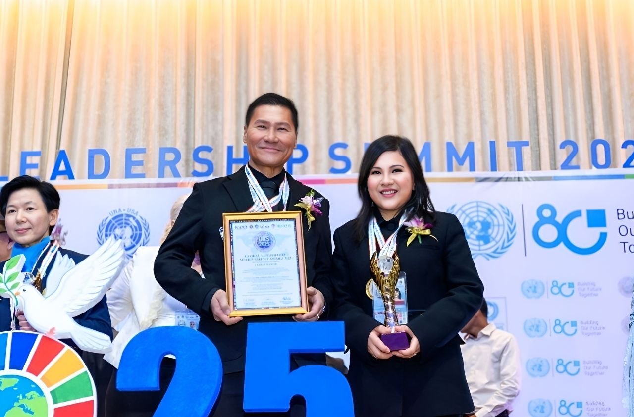 SHEKINAIH SIEW SIN YAP and J AARON K DAVID receiving their awards on stage at the Global Leadership Summit 2025, Bangkok — UN 80th Anniversary backdrop