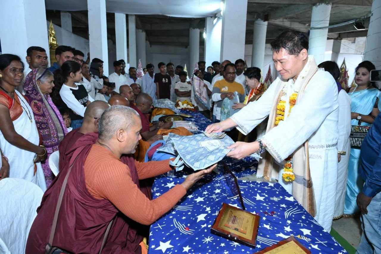 J AARON K DAVID offering monk robes to seated Buddhist monks at Tathagat Buddha Vihar, Nagpur