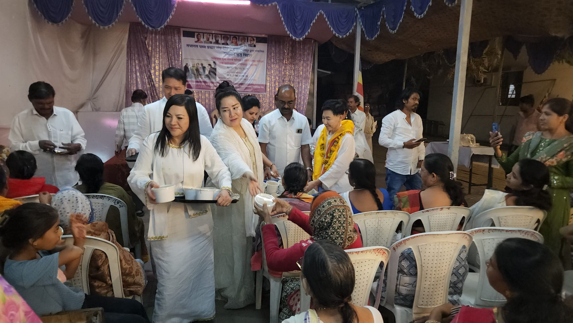 SHEKINAIH SIEW SIN YAP and J AARON K DAVID serving food to the seated community at Tathagat Buddha Vihar, Nagpur — Republic Day 2026