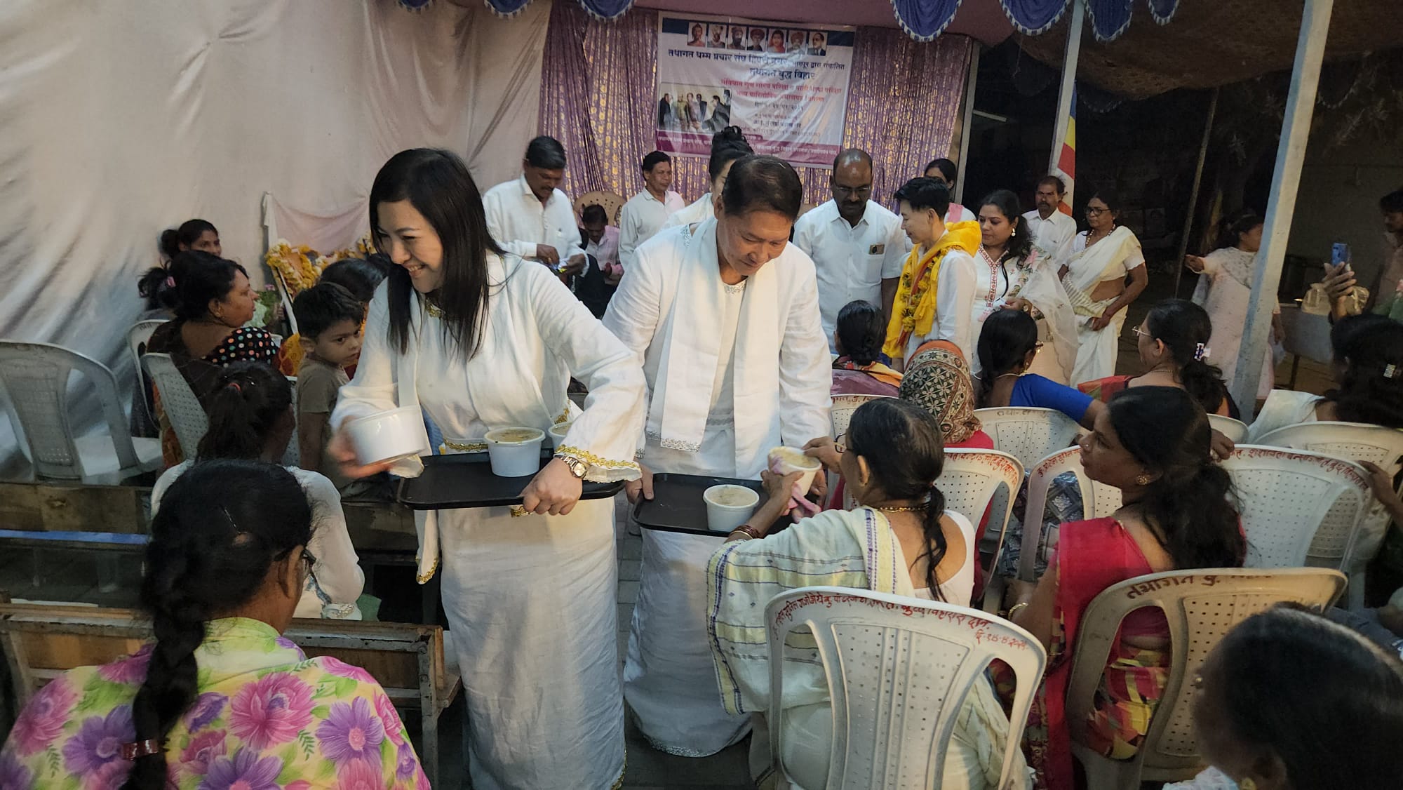 SHEKINAIH SIEW SIN YAP and J AARON K DAVID serving food to seated guests at Tathagat Buddha Vihar, Nagpur