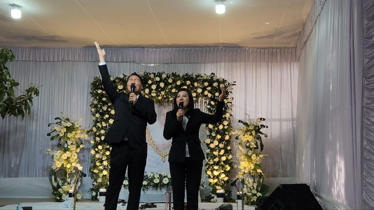 SHEKINAIH SIEW SIN YAP and J AARON K DAVID singing in ministry with hands raised at the funeral service stage, Sister Nivedita University, Kolkata, February 2026