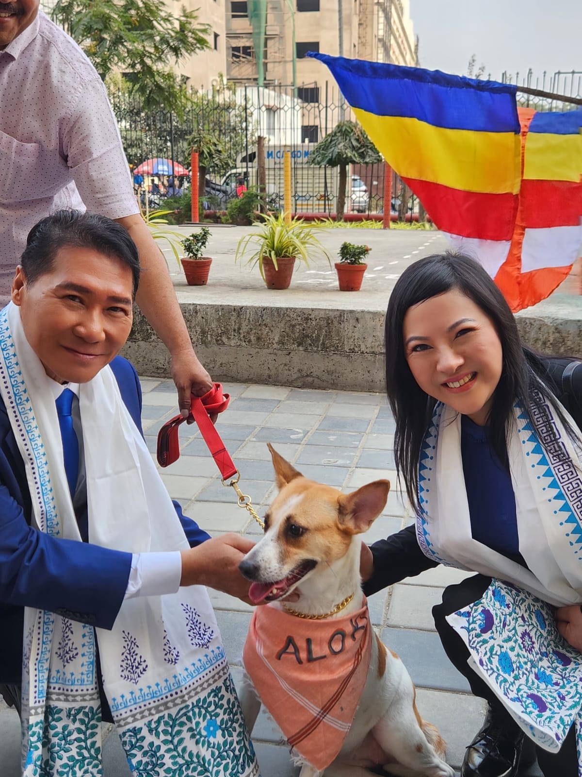 SHEKINAIH SIEW SIN YAP and J AARON K DAVID with Aloha, the monastery's rescued temple dog, beneath the Buddhist flag, Kolkata