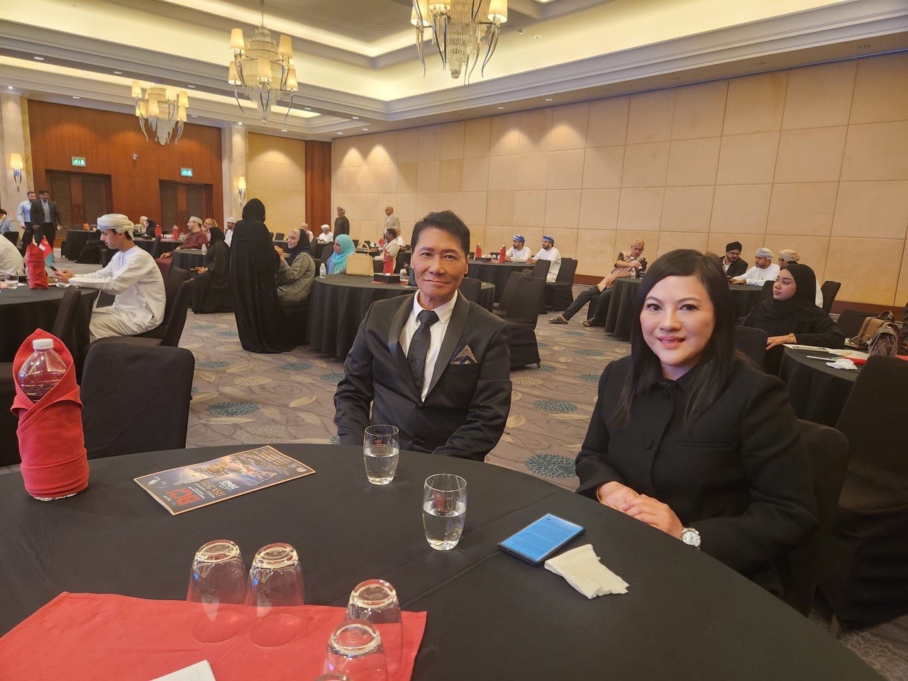 SHEKINAIH SIEW SIN YAP and J AARON K DAVID seated at the IISA 2026 gala ballroom among international delegates and Omani officials